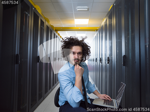 Image of engineer working on a laptop in server room