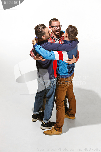Image of Three friends in casual colorful wear standing and laughing together.