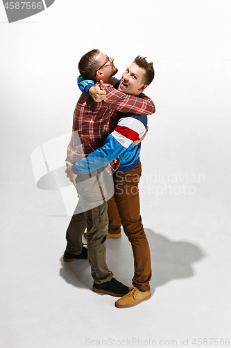 Image of Two friends in casual colorful wear standing and laughing together.