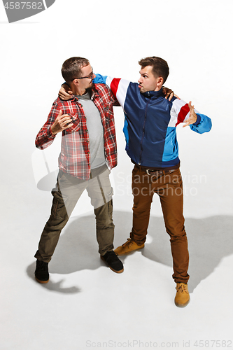 Image of Two friends in casual colorful wear standing and laughing together.