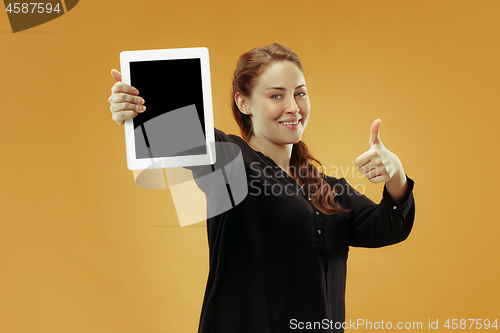 Image of Portrait of a confident casual girl showing blank screen of laptop isolated over studio background