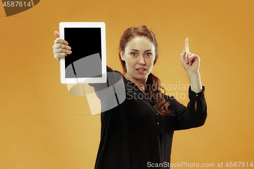 Image of Portrait of a confident casual girl showing blank screen of laptop isolated over studio background