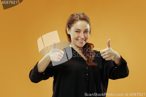 Image of The happy business woman standing and smiling against gold background.