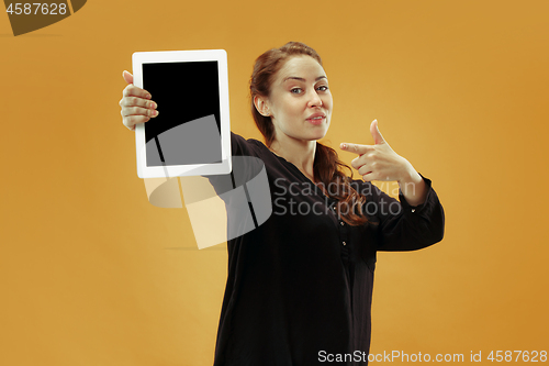 Image of Portrait of a confident casual girl showing blank screen of laptop isolated over studio background