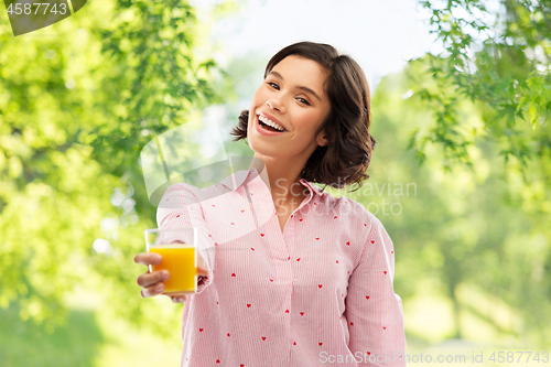 Image of happy young woman in pajama holding orange juice