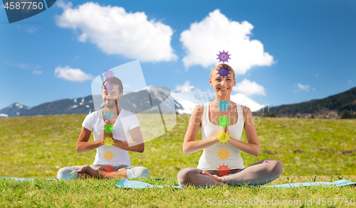 Image of couple doing yoga in lotus pose with seven chakras