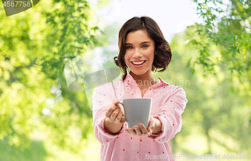 Image of happy young woman in pajama with mug of coffee