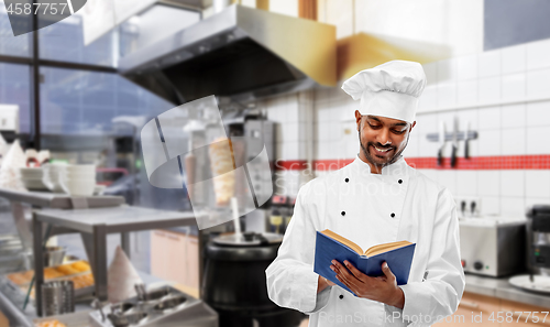 Image of happy indian chef reading cookbook at kebab shop