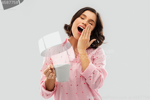 Image of happy yawning young woman in pajama with coffee