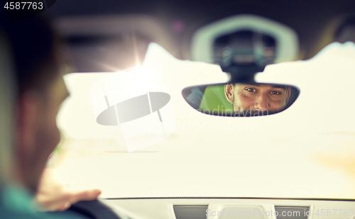 Image of rearview mirror reflection of man driving car