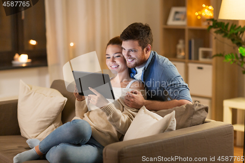 Image of happy couple using tablet pc at home in evening