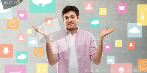 Image of young man shrugging over app icons on grey