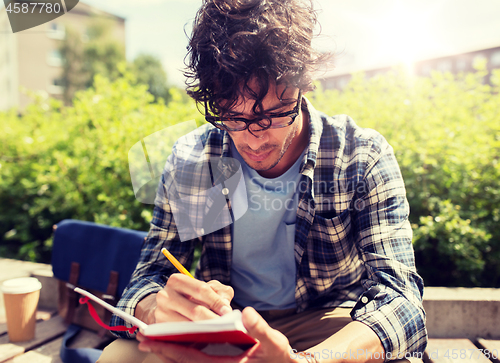 Image of man with notebook or diary writing on city street