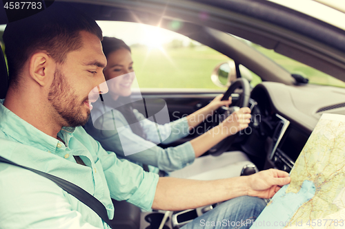 Image of happy man and woman with road map driving in car