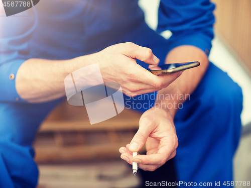 Image of auto mechanic smoking cigarette at car workshop