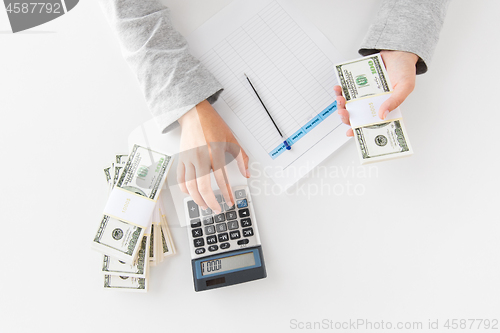 Image of hands with calculator and tax form counting money