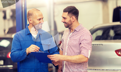 Image of auto mechanic with clipboard and man at car shop