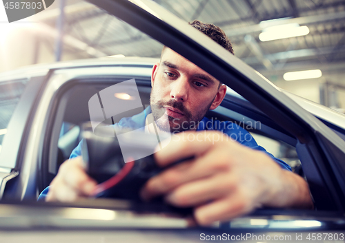 Image of mechanic man with diagnostic scanner at car shop