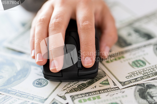 Image of close up of hand with computer mouse on money