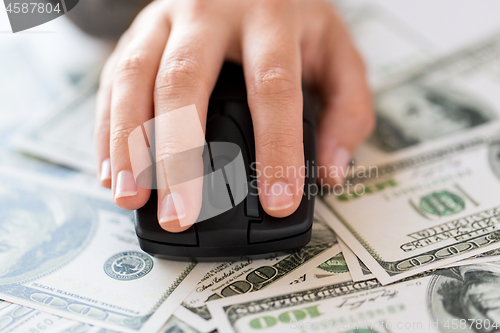 Image of close up of hand with computer mouse on money