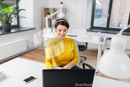 Image of businesswoman with headphones and laptop at office