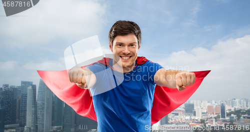 Image of man in red superhero cape over singapore city