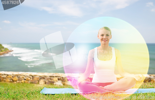Image of woman doing yoga in lotus pose with rainbow aura