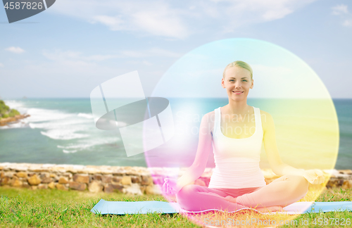 Image of woman doing yoga in lotus pose with rainbow aura