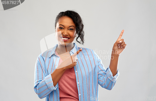 Image of happy african american woman pointing finger up