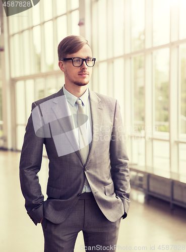 Image of young businessman in suit and glasses at office