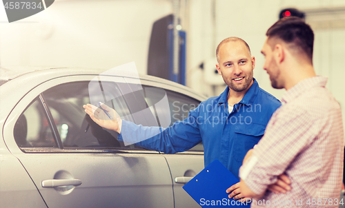 Image of auto mechanic with clipboard and man at car shop