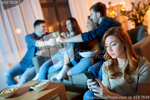 Image of sad young woman with smartphone at home party