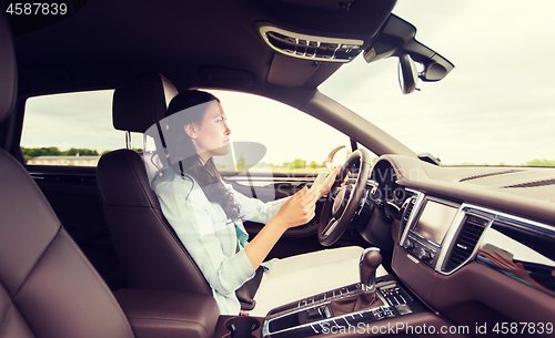 Image of happy woman driving car with smarhphone