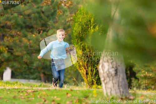 Image of The boy happily runs through the park on the green grass