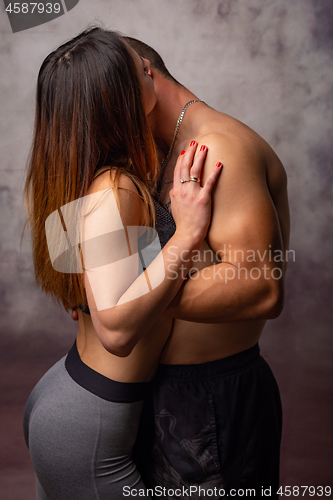 Image of Two young men sporting physique kiss each other, turning away