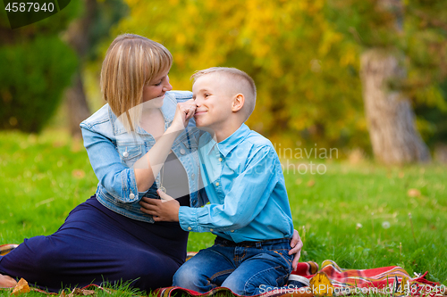 Image of Mom tenderly took her teen\'s nose while relaxing in a clearing in a park