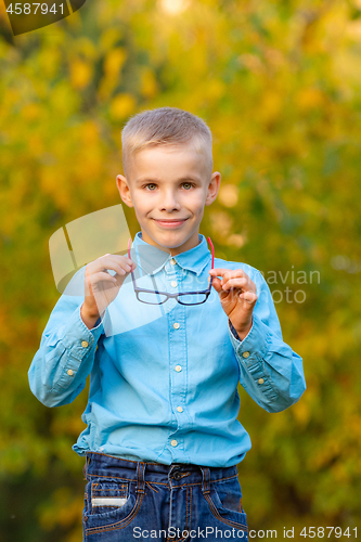 Image of Portrait of a cheerful boy taking off his glasses