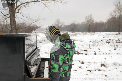 Image of Boy playing piano outdoors