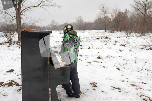 Image of Boy playing piano outdoors