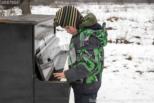 Image of Boy playing piano outdoors