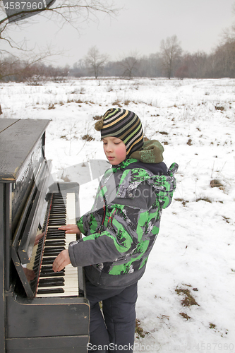 Image of Boy playing piano outdoors