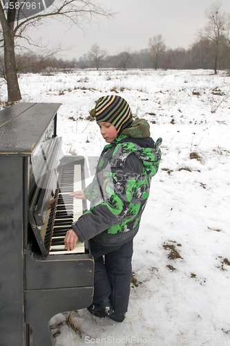 Image of Boy playing piano outdoors