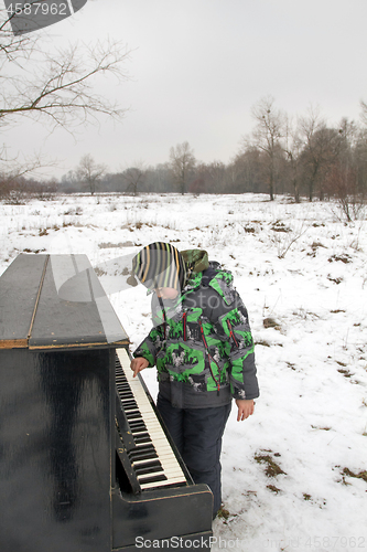 Image of Boy playing piano outdoors