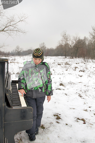 Image of Boy playing piano outdoors