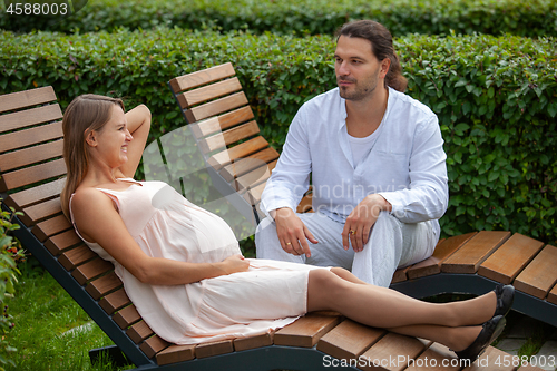 Image of Pregnancy. Happy couple . Relax on the sun loungers