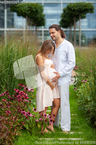 Image of Smiling young man and pregnant woman in a park