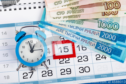 Image of The calendar marks the fifteenth, with banknotes and watches lying next to