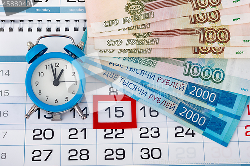 Image of Calendar with a dedicated 15 number, a pack of Russian money and a clock