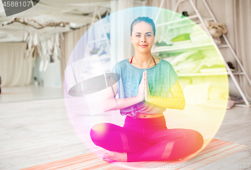 Image of woman meditating in lotus pose at yoga studio