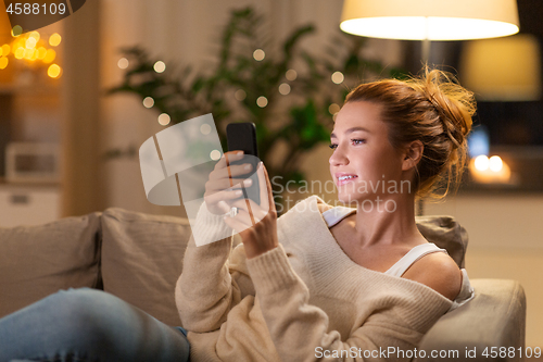 Image of happy young woman with smartphone at home